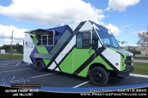 food truck with geometric pattern parked on pavement under blue sky with service window open