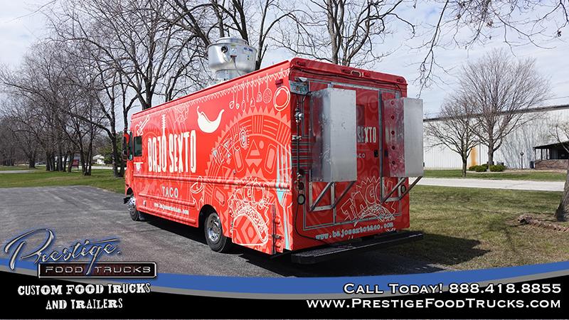 rear 3/4 view of red food truck showing rear door and driver's side graphics