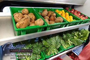 close up of vegetables in baskets on shelves inside mobile produce truck