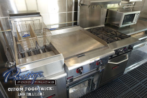 photo of food truck interior showing fryer baskets, a grill, a stove top and a toaster oven