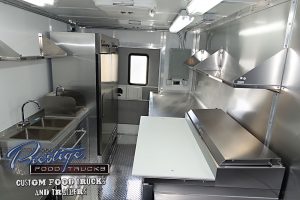 food truck interior with sinks, food prep table and fridge