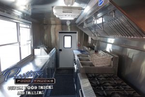 food truck interior showing stove, fryers, service window and back door