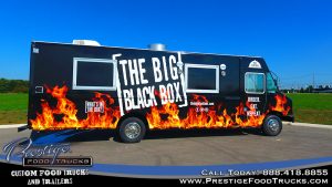 the big black box food truck with graphics of flames on a black background