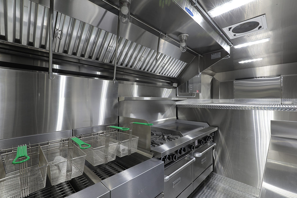 stainless steel food truck interior with oven, cooktop, and fryer baskets