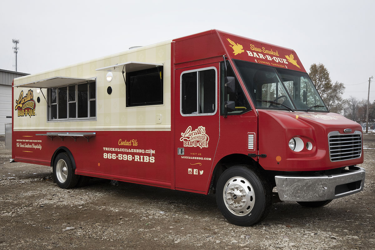front 3/4 angle photo of a red and cream colored food truck with serving windows open