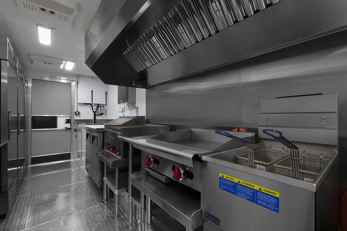 food truck interior kitchen photo showing deep fryer, griddle, sandwich prep table and exhaust hood
