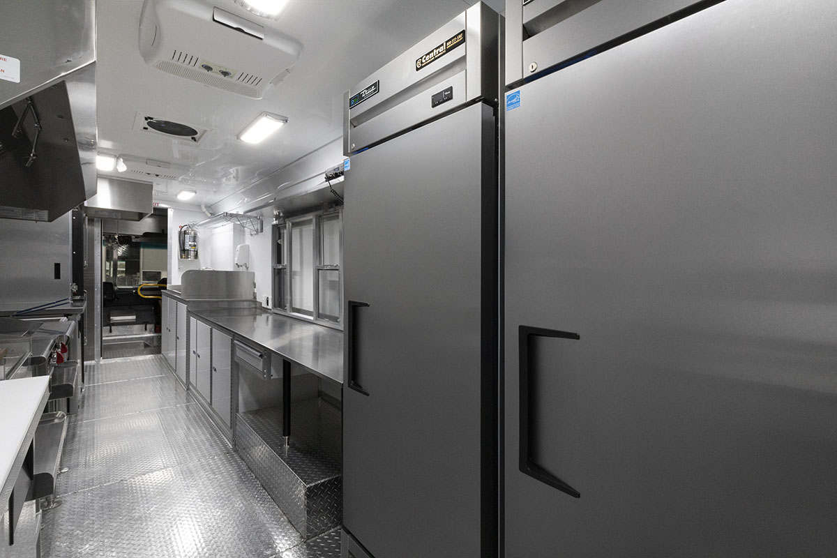 food truck interior kitchen photo showing fridges, counter, and sinks with driver door open