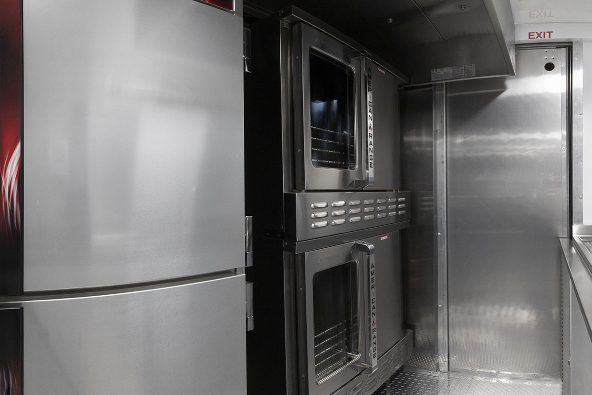 food truck interior kitchen photo showing proofing cabinet, ovens and closed driver door partition