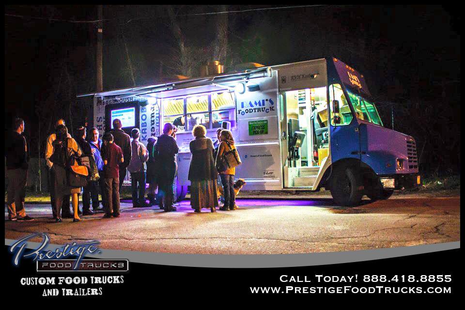 line of people outside lit up food truck at night