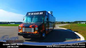 photo of a black food truck with flame graphics named the big black box
