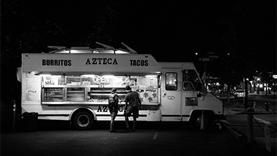 black and white photo of a burrito and taco food truck at night