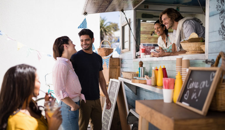 smiling food truck workers take a couple's order