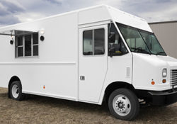 white food truck parked on grass on a cloudy day