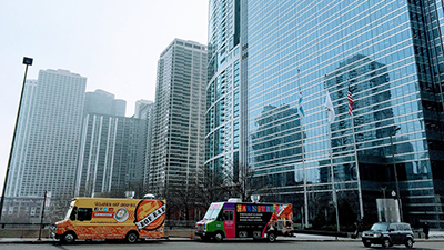 two food trucks parked in front of skyscrapers in a city downtown