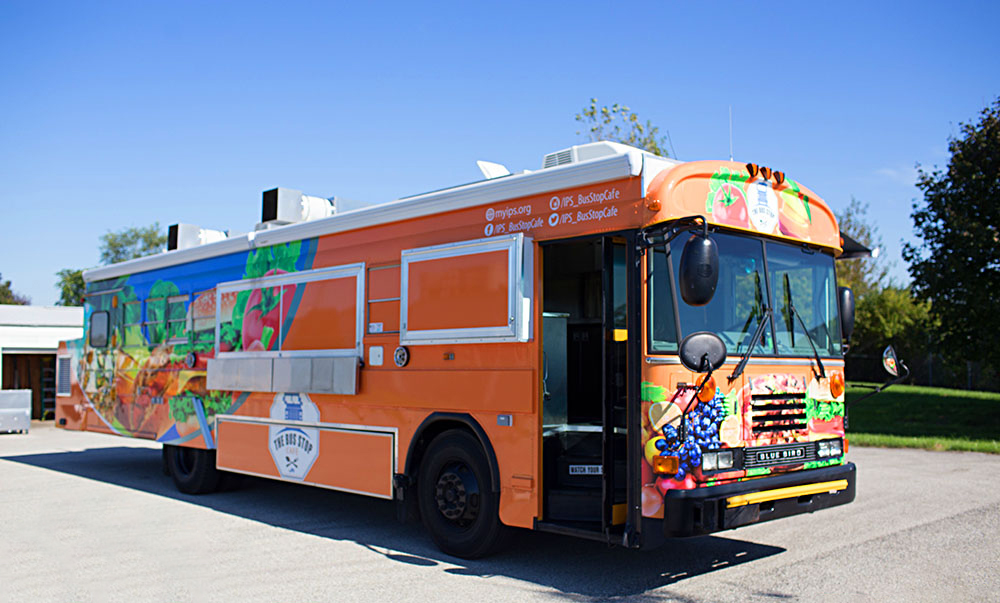 orange school bus food truck parked on asphalt under a blue sky