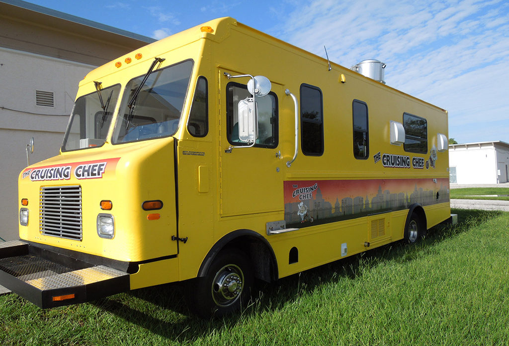 yellow food truck parked on grass under a blue sky