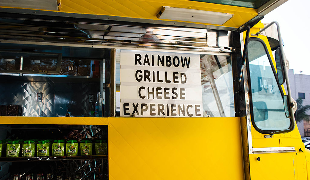 menu window on the side of a yellow food truck reads: rainbow grilled cheese experience