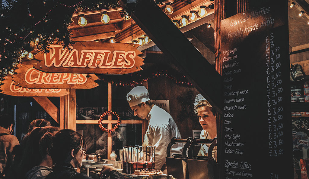 photo of male and female chefs selling from a food truck with signs for waffles and crepes