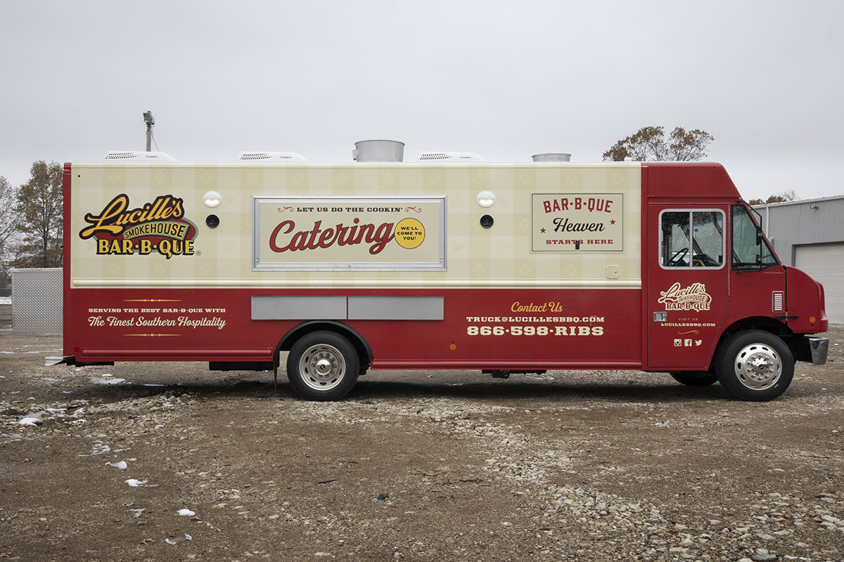 passenger side photo of a red and cream colored food truck with serving windows closed and exterior lights on