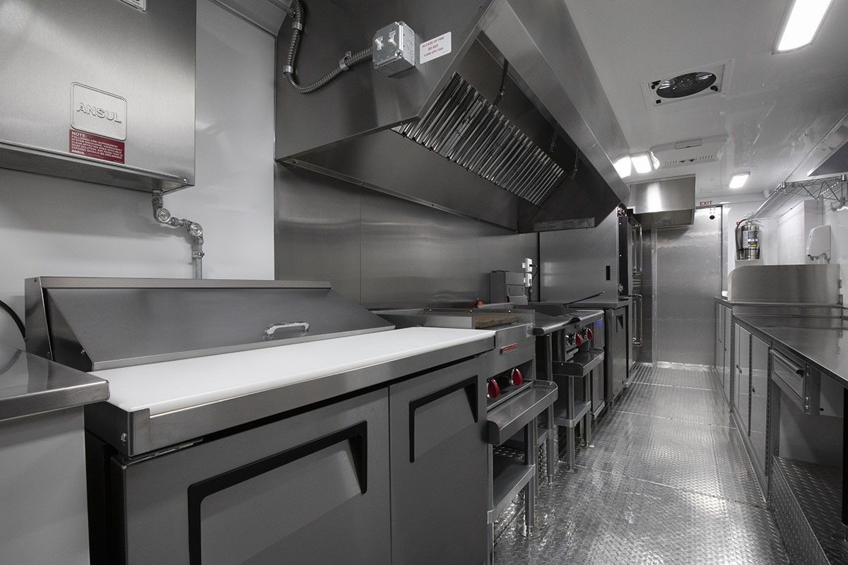 food truck interior kitchen photo showing sanwich prep table, exhaust hood, and griddle