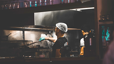man wearing a hairnet working in a restaurant kitchen