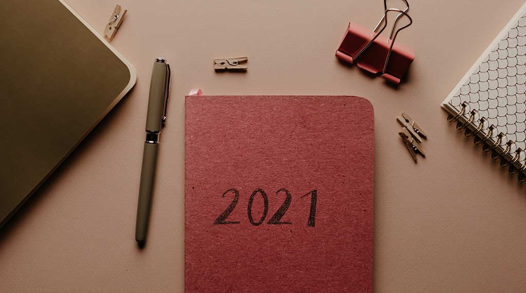 photo of a desk with office supplies and a red notebook with "2021" on the cover