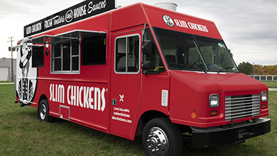 red and black food truck parked in a grassy field